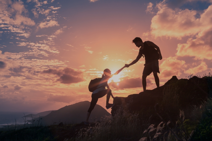 Hikers helping each other out on a mountain. Financial Advisors